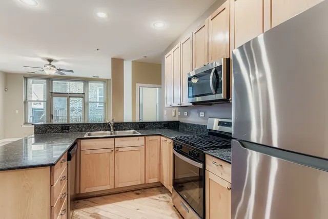 a kitchen with stainless steel appliances granite countertop a sink stove and refrigerator