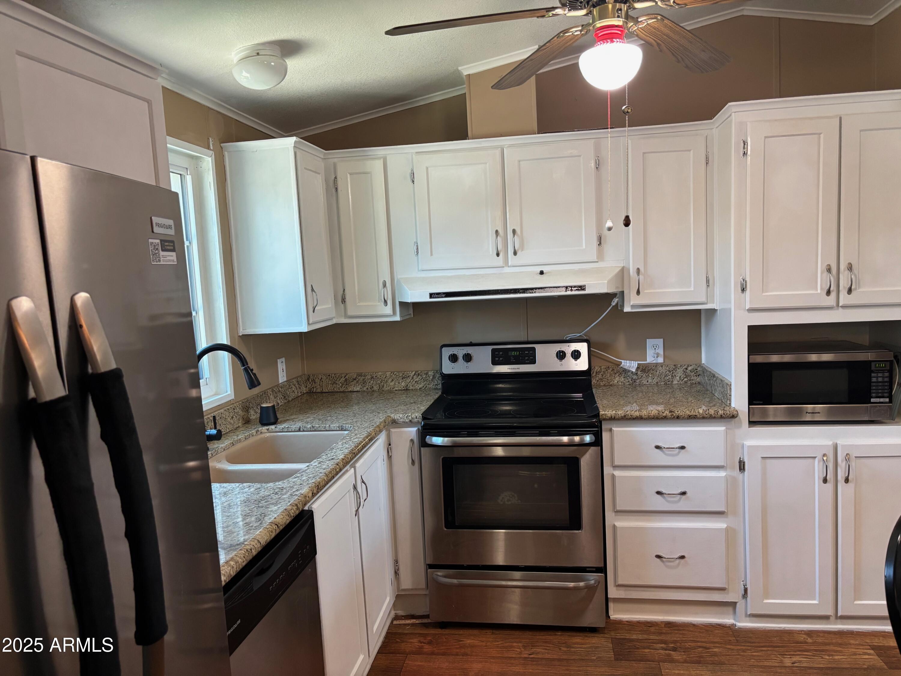 a kitchen with granite countertop white cabinets and stainless steel appliances