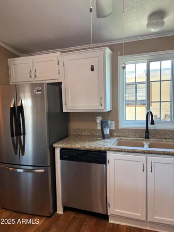 a kitchen with stainless steel appliances granite countertop a sink a refrigerator a stove and white cabinets with wooden floor