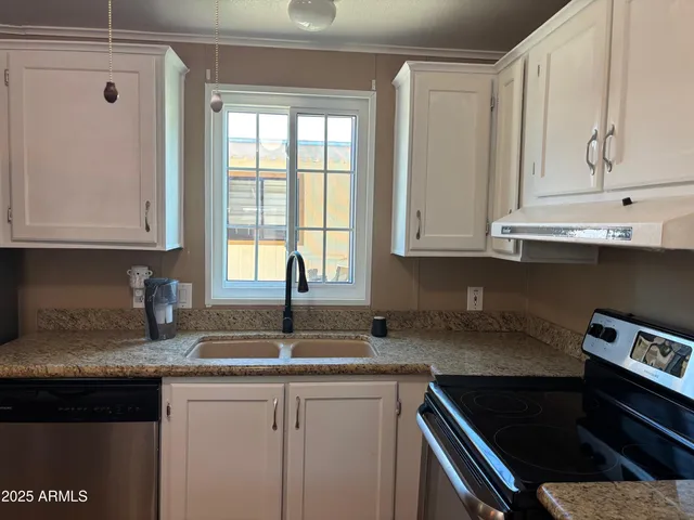 a kitchen with granite countertop a sink stove and cabinets