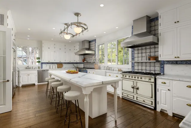 a kitchen with stainless steel appliances a dining table chairs sink and stove top oven