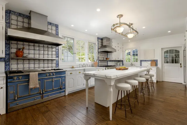 a kitchen with a dining table wooden floor and stainless steel appliances