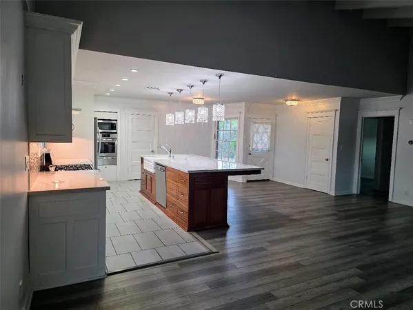 a large kitchen with stainless steel appliances a large counter top a stove and a wooden floors
