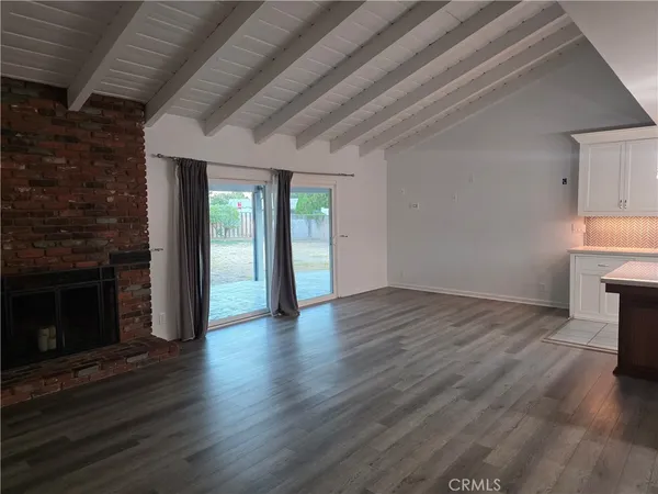 an empty room with wooden floor fireplace and windows