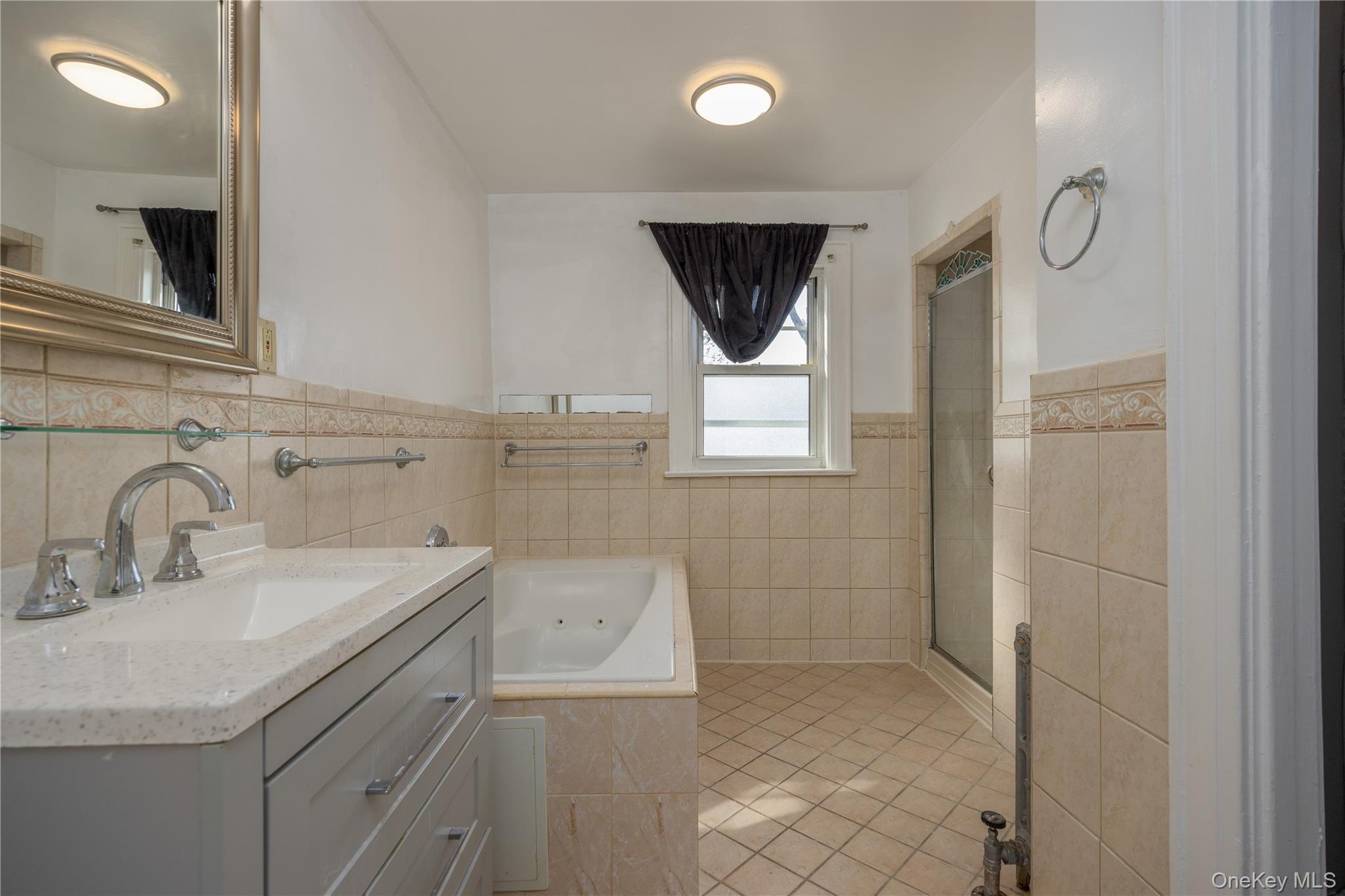 179-65 Selover Road Queens, NY 11434 - Photo 17 of 33 Primary Bathroom featuring a light gray vanity with three drawers, an integrated sink, coordinating countertop, chrome fixtures, a jetted tub, and a glass-enclosed shower
