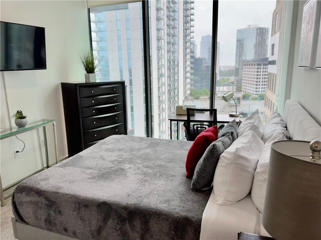 3382 Peachtree Road Northeast, Unit S12 Atlanta, GA 30326 - Photo 12 of 29 a bedroom with a bed and dresser with mirror