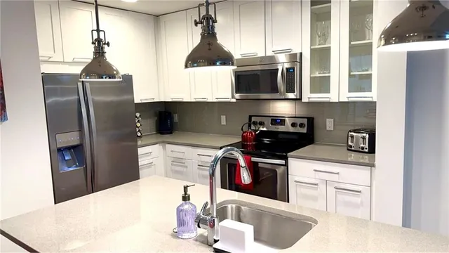 a kitchen with stainless steel appliances granite countertop a sink a stove and a refrigerator