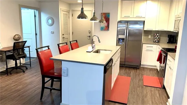 a kitchen with stainless steel appliances granite countertop a table chairs and a refrigerator