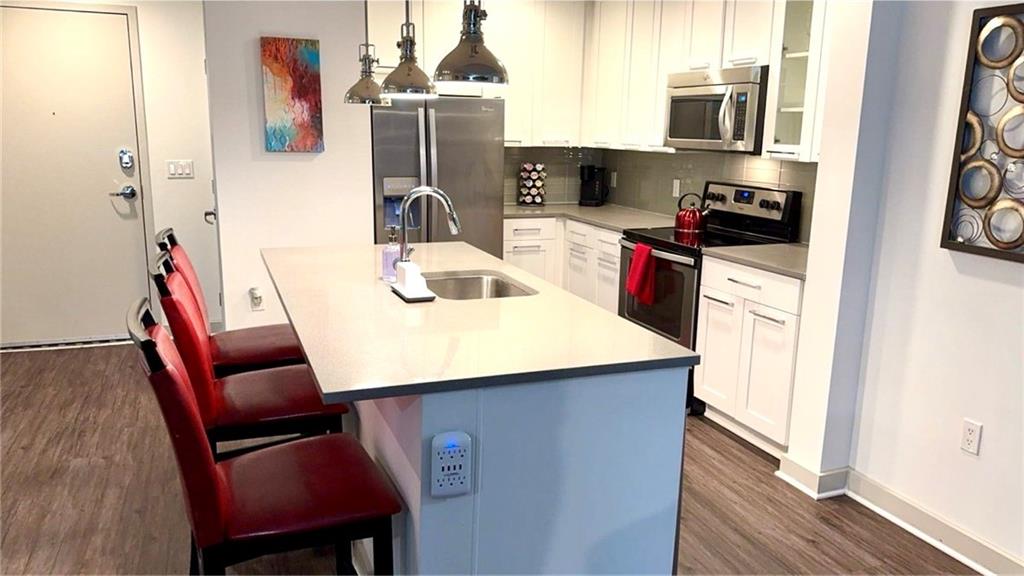 3382 Peachtree Road Northeast, Unit S12 Atlanta, GA 30326 - Photo 24 of 29 a kitchen with stainless steel appliances kitchen island granite countertop a sink dishwasher a stove a refrigerator and a dining table with wooden floor