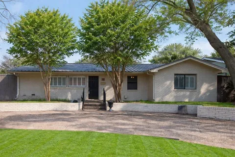 a front view of house with yard and trees in the background