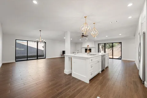 a large white kitchen with a large window a island a sink and stainless steel appliances