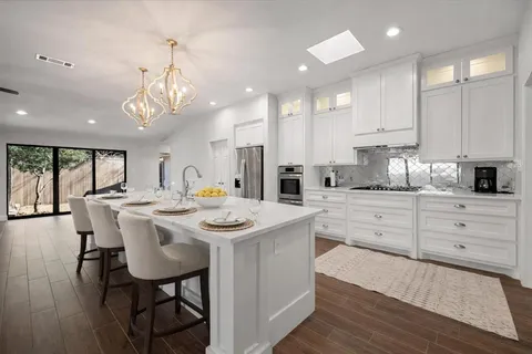 a kitchen with a dining table chairs sink and cabinets