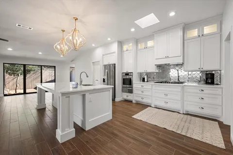 a kitchen with white cabinets stainless steel appliances and window
