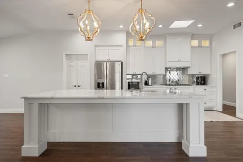 a kitchen with stainless steel appliances granite countertop a sink a refrigerator and cabinets