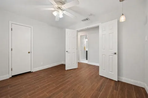 an empty room with wooden floor and a ceiling fan