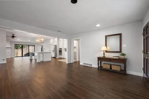 a view of an empty room with wooden floor and a ceiling fan
