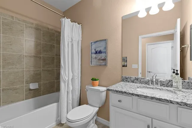 a bathroom with a granite countertop sink a toilet and shower