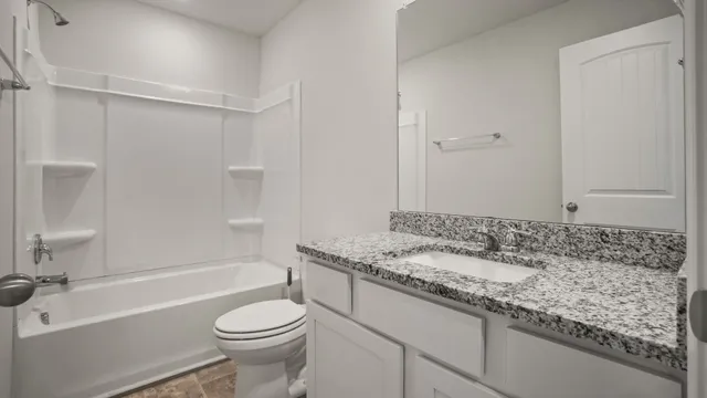 a bathroom with a granite countertop sink toilet and a mirror