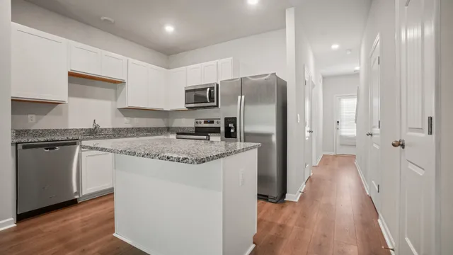 a kitchen with stainless steel appliances granite countertop a refrigerator a stove and a sink