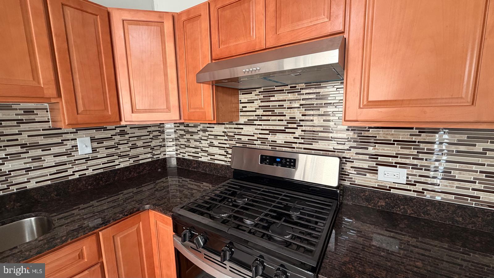 4406 Higbee Street Philadelphia, PA 19135 - Photo 12 of 36 a kitchen with granite countertop a stove sink and cabinets