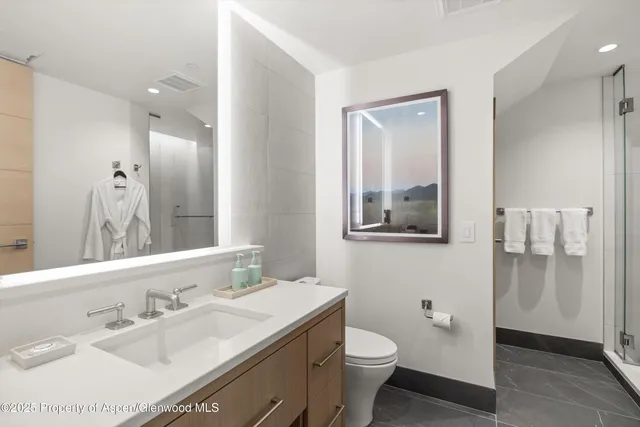 a bathroom with a sink vanity granite toilet and a mirror