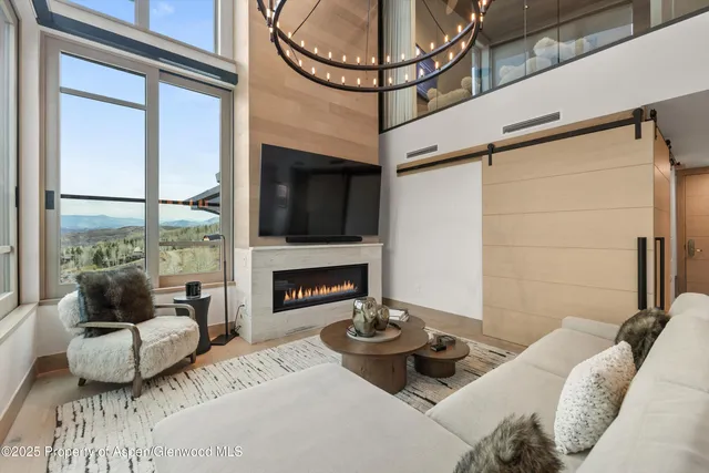 a living room with furniture a fireplace and a floor to ceiling window