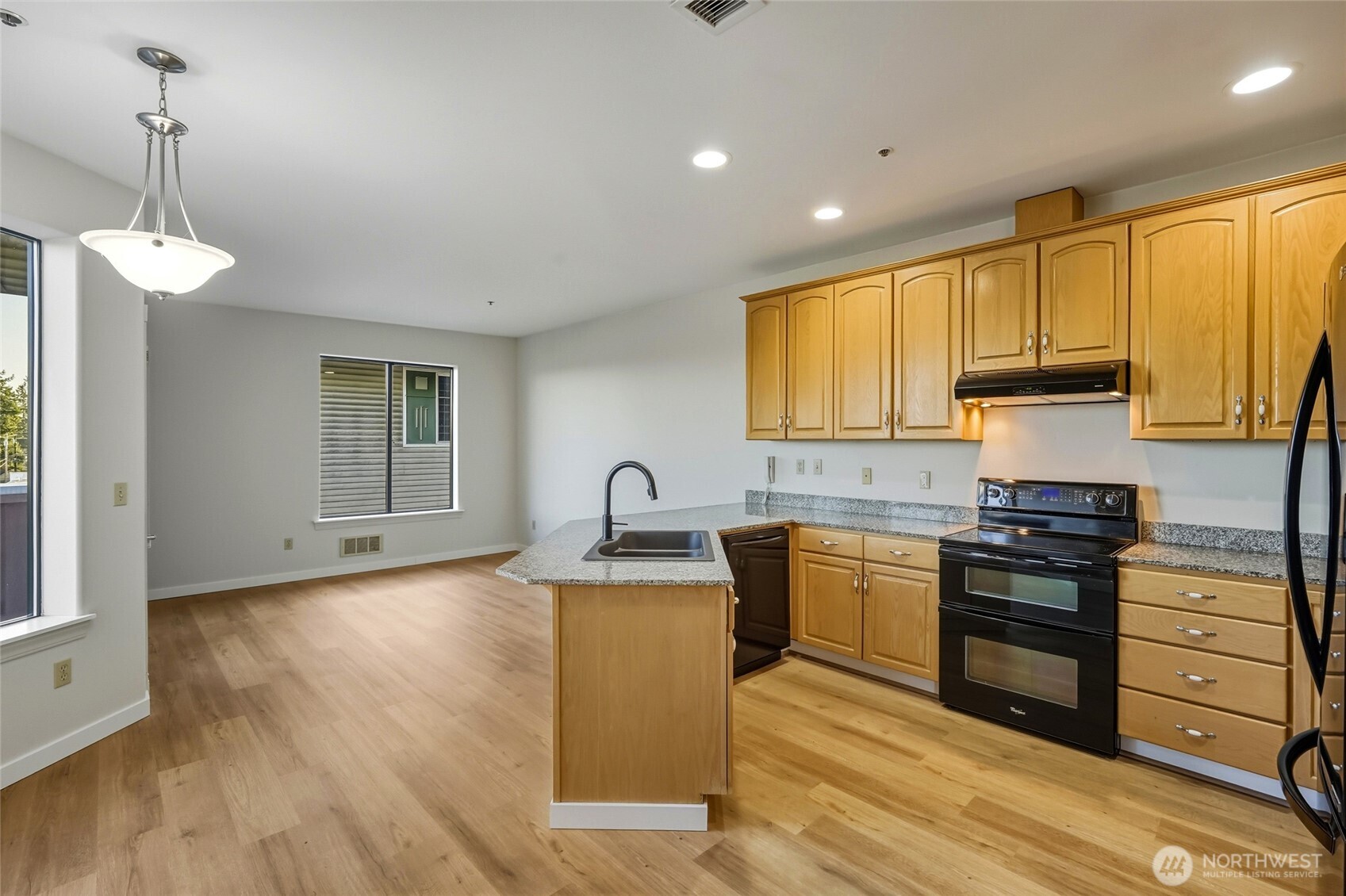 3501 Colby Avenue, Unit 311 Everett, WA 98201 - Photo 4 of 28 a kitchen with kitchen island granite countertop a sink cabinets and wooden floor