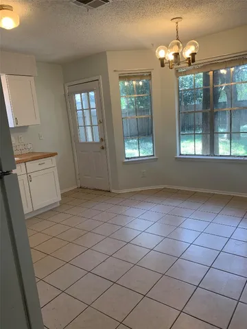 an empty room with chandelier fan and windows