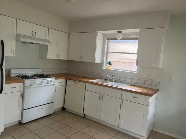 a kitchen with white cabinets appliances a sink and a window
