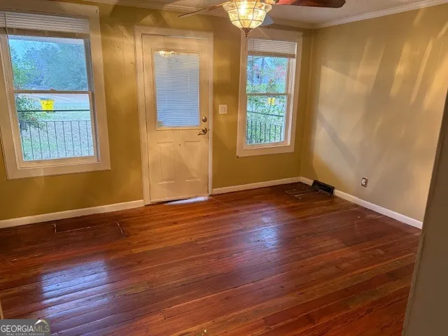 an empty room with wooden floor and windows