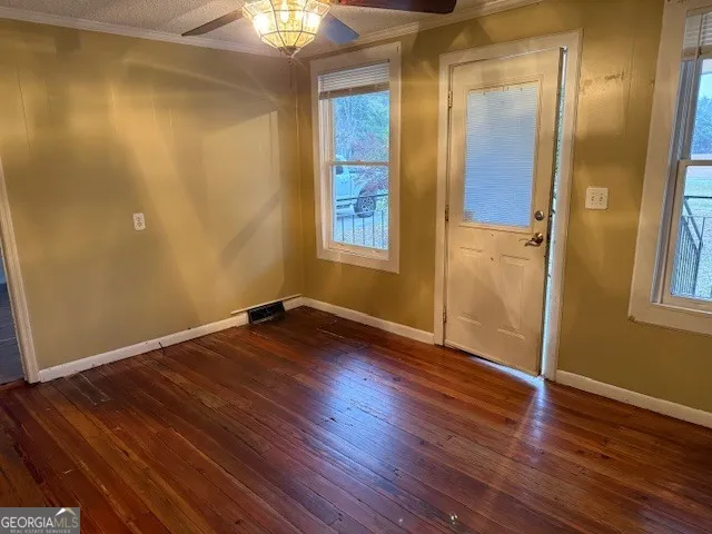 an empty room with wooden floor and windows