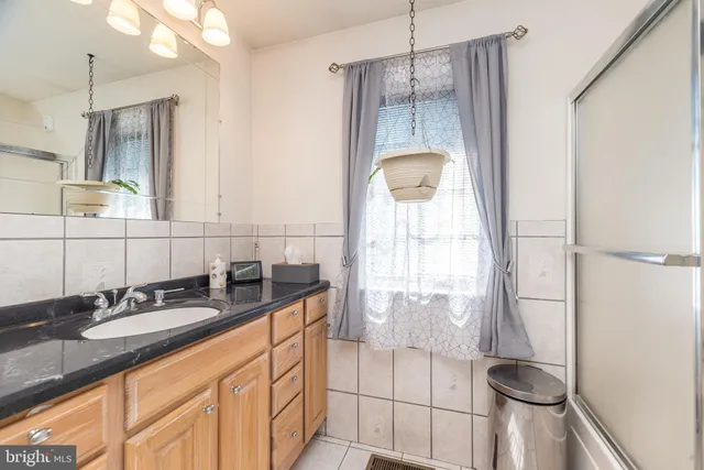 a spacious bathroom with a granite countertop sink a mirror a bathtub and next to a window