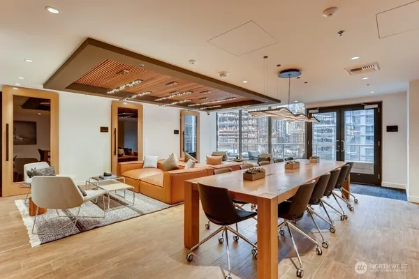 a living room with stainless steel appliances furniture a large window with kitchen view