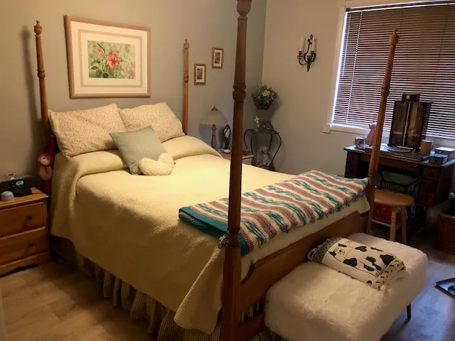 a bedroom with a bed a dresser and next to a window