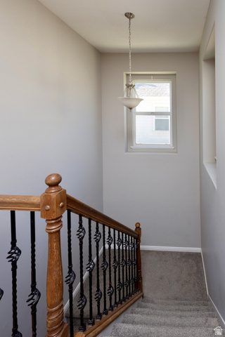 11751 Lake Run Road South Jordan, UT 84009 - Photo 23 of 38 Staircase featuring wood handrails with wrought iron balusters, neutral-toned carpeting, and a pendant light fixture