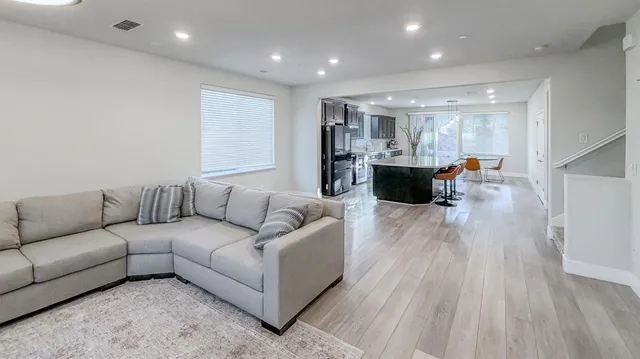 a living room with stainless steel appliances furniture a rug and a kitchen view