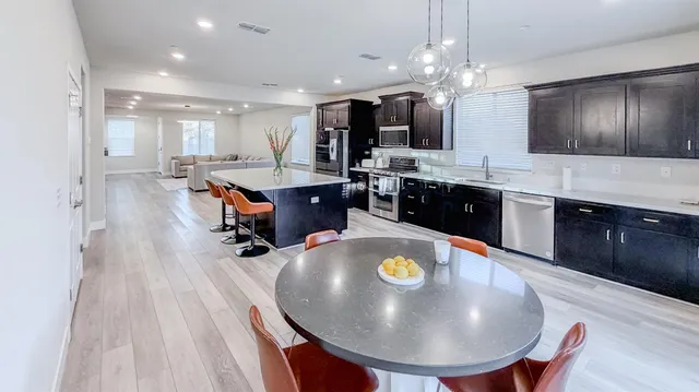 a large kitchen with stainless steel appliances a large counter top a stove and a refrigerator