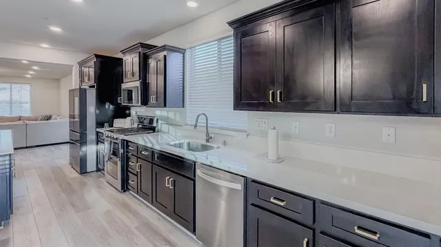 a large kitchen with stainless steel appliances kitchen island granite countertop a sink dishwasher a stove a refrigerator and a dining table with wooden floor