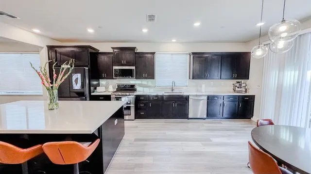 a dining room with stainless steel appliances kitchen island a table chairs and a refrigerator