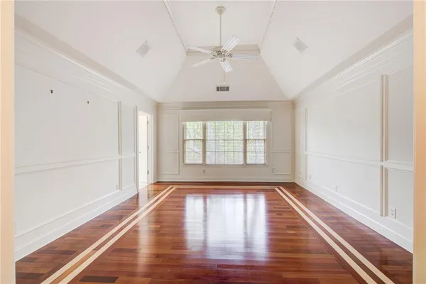 an empty room with windows and ceiling fan