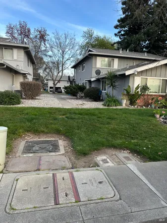 a view of a white house next to a yard with big trees