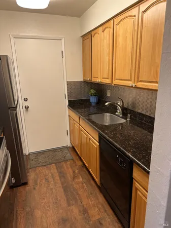 a kitchen with granite countertop a sink a stove a refrigerator and cabinets