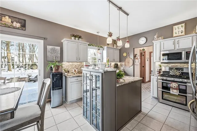 a kitchen with stainless steel appliances kitchen island granite countertop a refrigerator a stove a oven a dining table and chairs with wooden floor
