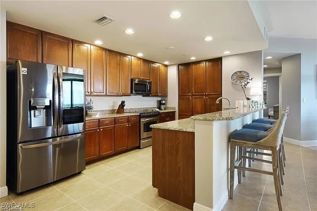 a kitchen with granite countertop a refrigerator a stove a sink a dining table and chairs