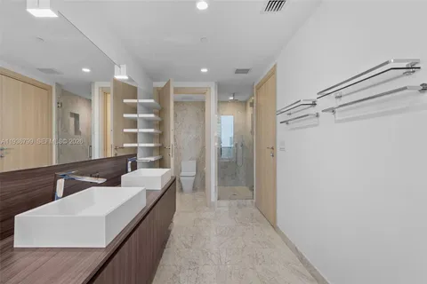 a bathroom with a double vanity sink a large mirror and shower