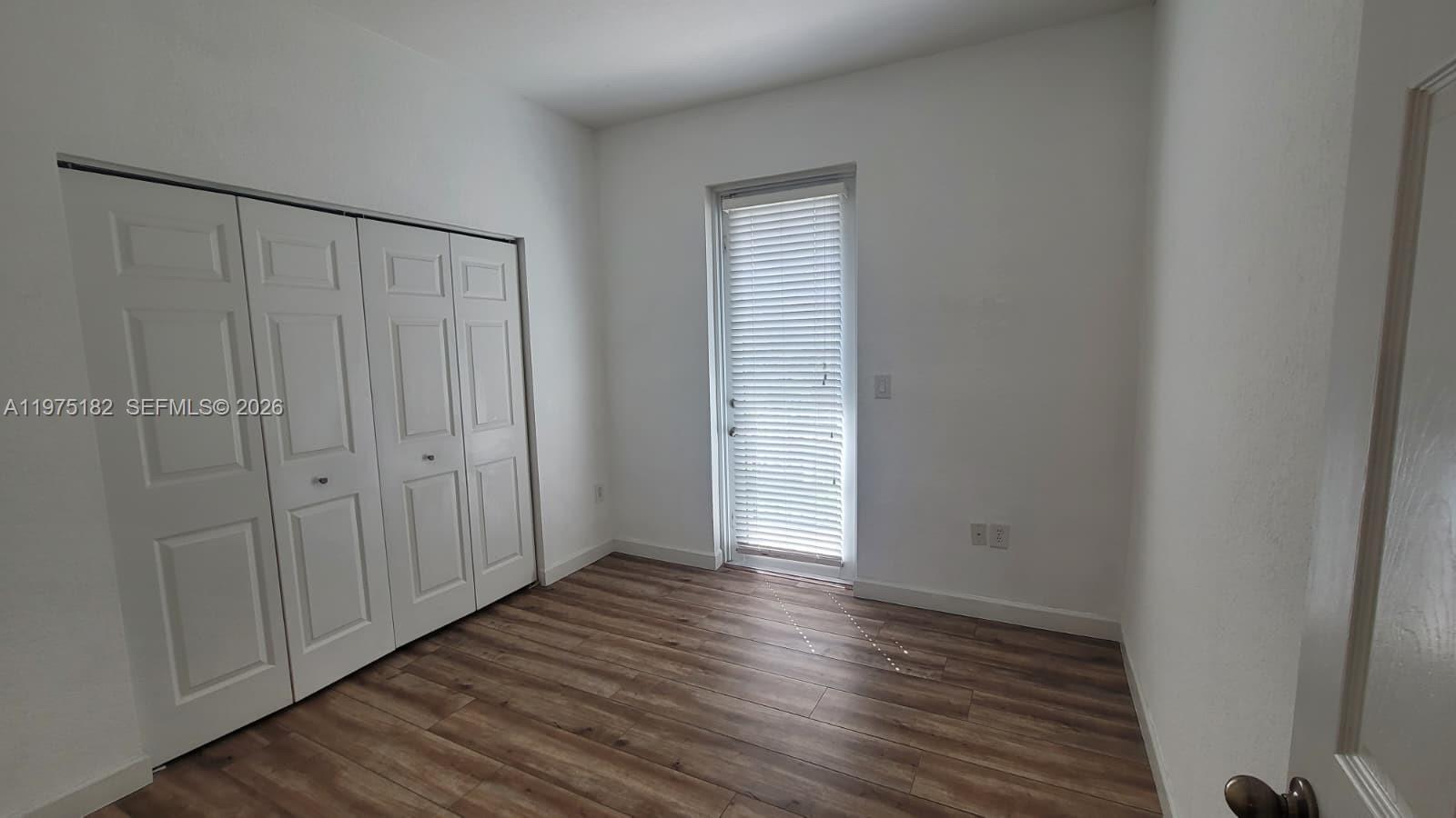 12842 Southwest 134th Street Miami, FL 33186 - Photo 14 of 22 a view of an empty room with wooden floor and a window