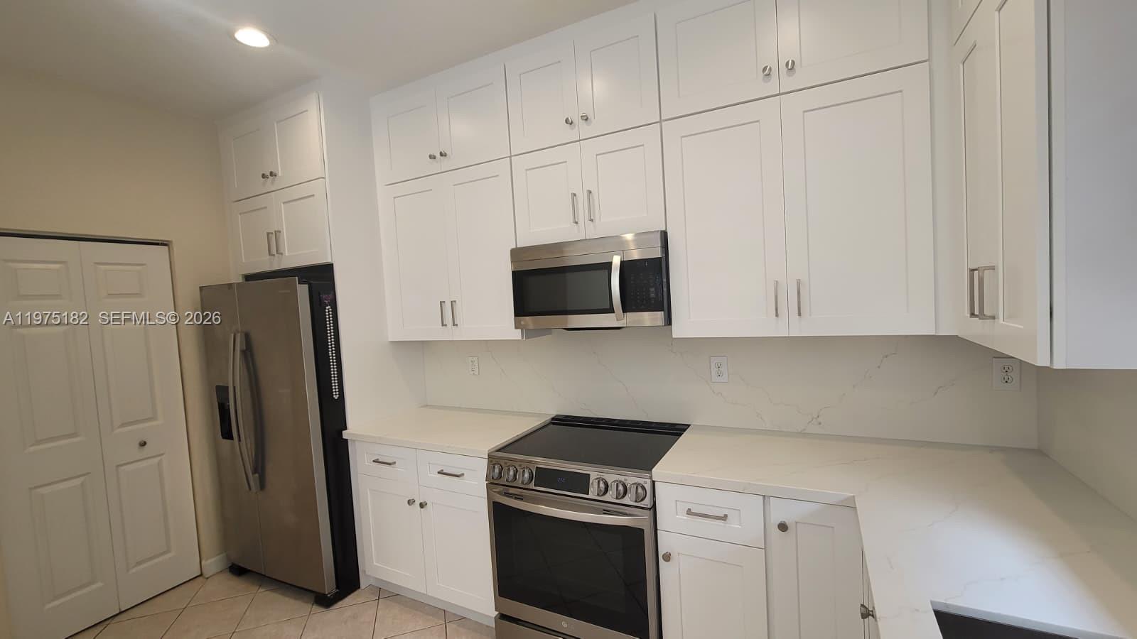 12842 Southwest 134th Street Miami, FL 33186 - Photo 3 of 22 a kitchen with stainless steel appliances white cabinets and a refrigerator