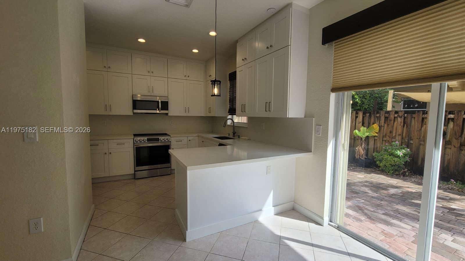 12842 Southwest 134th Street Miami, FL 33186 - Photo 5 of 22 a kitchen with kitchen island granite countertop a refrigerator a sink and a stove