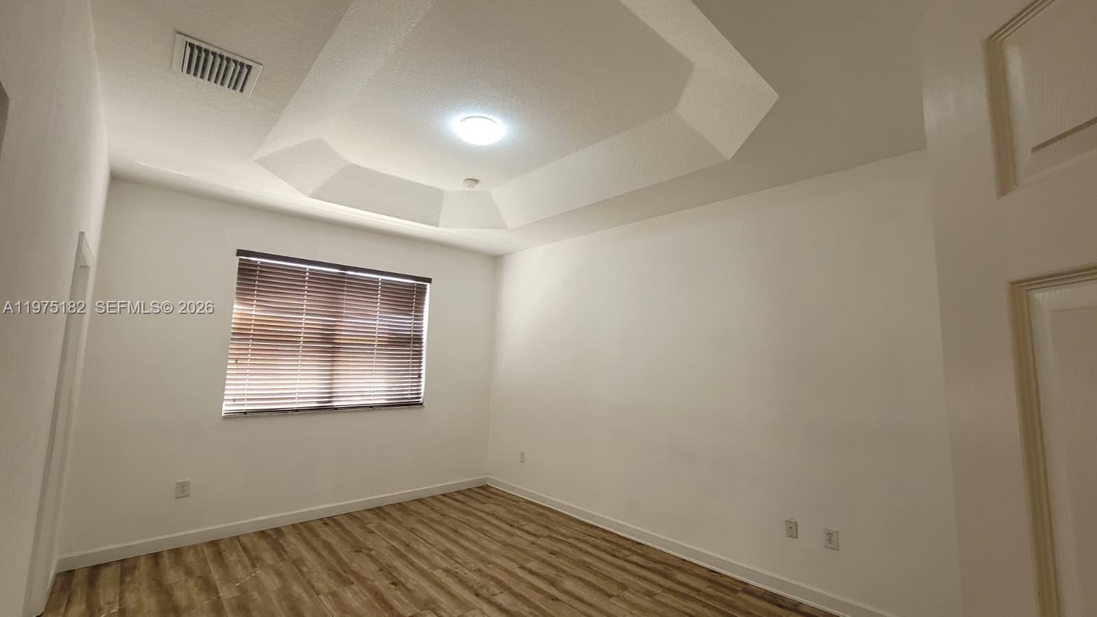 12842 Southwest 134th Street Miami, FL 33186 - Photo 10 of 22 a view of an empty room with wooden floor and a window