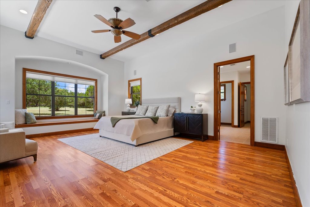 1525 Springlake Drive Dripping Springs, TX 78620 - Photo 13 of 38 a spacious bedroom with a large bed and a chandelier fan